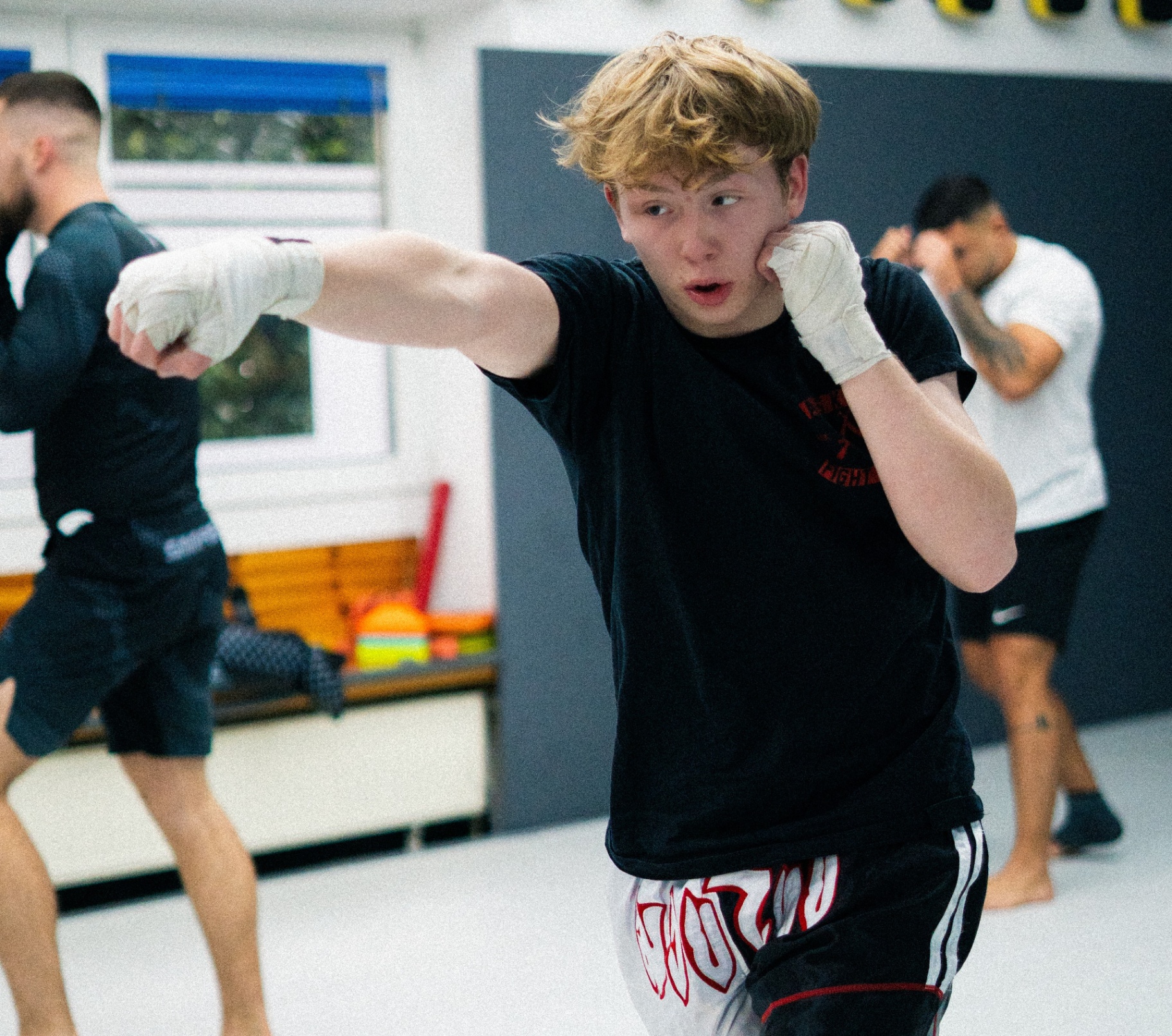 Boxer in Boxhandschuhen trainiert Schlagkombinationen an den Pratzen des Coaches